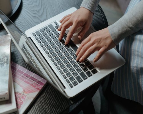 Person typing on laptop keyboard with good posture